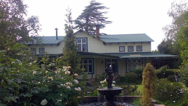 A two-story house with a stone fountain in the front garden. - Highland Rose Country House & Serenity Spa (Dullstroom)