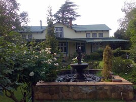 Una casa de dos pisos con una fuente de piedra en el jardín delantero.