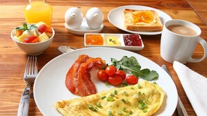 A breakfast setting with an omelette, bacon, cherry tomatoes, and a fruit bowl. - Sandton Slippers (Sandton)
