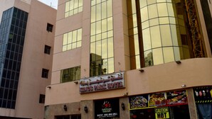 A tall hotel with a glass facade, a sign for a buffet, BBQ, and grill, and a caution sign for hot food. - Kings Park Hotel (Dubai)
