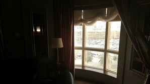 A dimly lit room with a large window, a lamp, and a mirror. - Kings Park Hotel (Dubai)