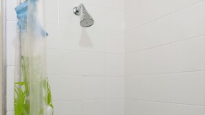 A shower with white tiles, a showerhead, and a hand soap dispenser. - Omar do Rio - A1208 (Rio de Janeiro)