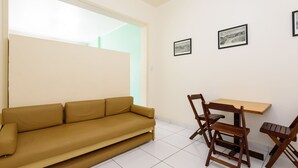 A living room with a sofa, wooden dining table, chairs, and two framed pictures on the wall. - Omar do Rio - A1208 (Rio de Janeiro)