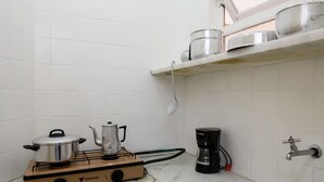 A small kitchen with white tiled walls, a gas stove, a coffee maker, and a sink. - Omar do Rio - A1208 (Rio de Janeiro)