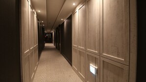 A hallway with a carpeted floor, recessed lighting, and wooden paneling on the walls. - Hotel Cheese (Busan)