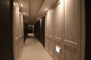 A hallway with a carpeted floor, recessed lighting, and wooden paneling on the walls. - Hotel Cheese (Busan)