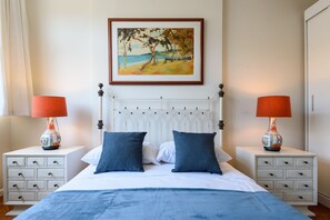 A bedroom with a bed, two nightstands, two lamps, a framed painting, and a white headboard. - Omar do Rio - HG904 (Rio de Janeiro)