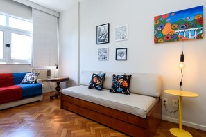 A modern living room with a sofa, a red and blue couch, a small round table, and a wall with framed artwork. - Omar do Rio - HG904 (Rio de Janeiro)