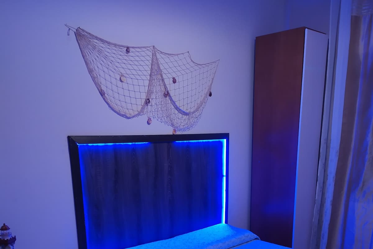 A bedroom with a bed, a nightstand, a wardrobe, and a decorative hanging net.