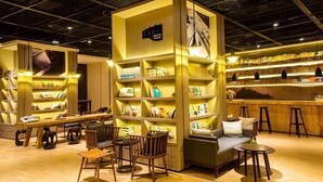 A bookstore with multiple shelves of books, a seating area with chairs and tables, and a bar area with stools. - Atour S Hotel Chunxi Road Chengdu (Chengdu)