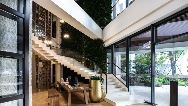 A modern interior with a staircase, wooden flooring, a large potted plant, and a desk with a computer. - Atour S Hotel Chunxi Road Chengdu (Chengdu)