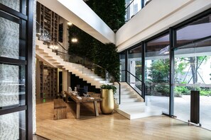 A modern interior with a staircase, wooden flooring, a large potted plant, and a desk with a computer. - Atour S Hotel Chunxi Road Chengdu (Chengdu)