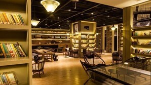 A library with bookshelves, tables, chairs, and a glass display case. - Atour S Hotel Chunxi Road Chengdu (Chengdu)
