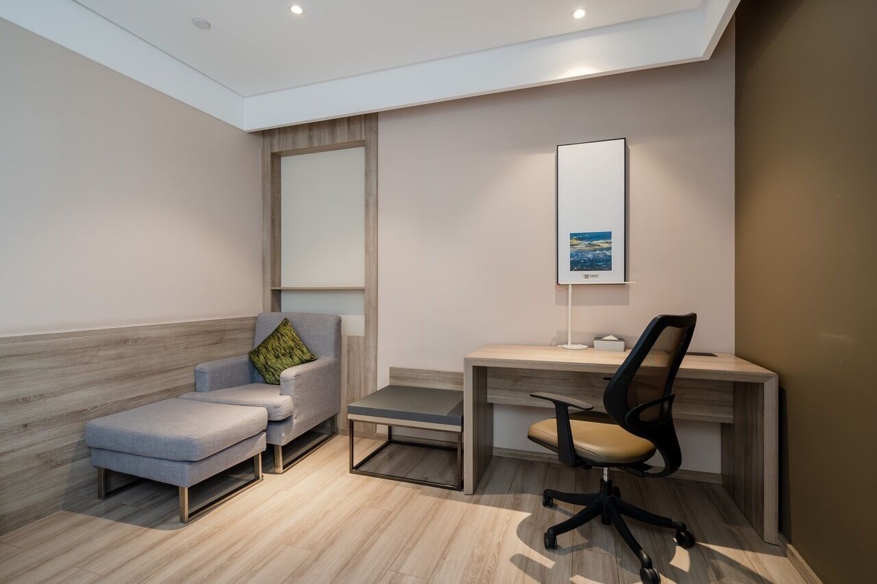 A modern office space with a desk, office chair, and a cushioned seating area.