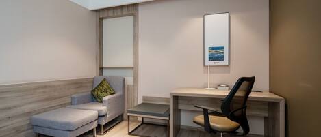 A modern office space with a desk, office chair, and a cushioned seating area.