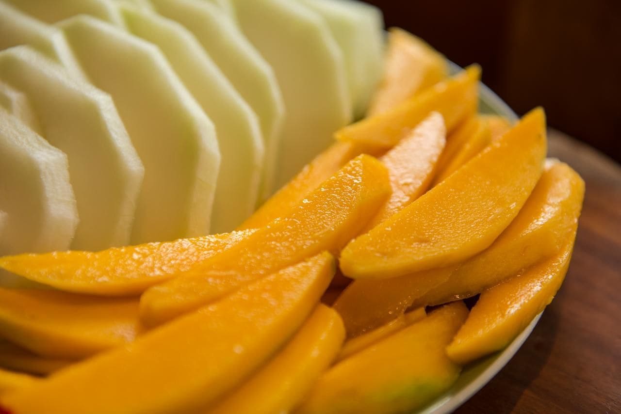 A plate with sliced mango and a white dessert.