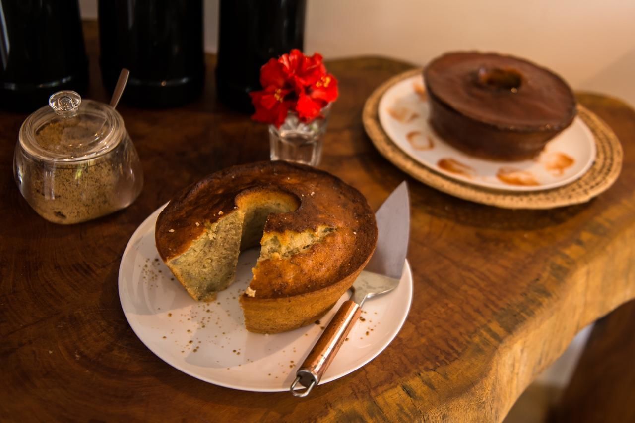 Une table en bois sur laquelle se trouve une assiette avec un gâteau, un bocal d’épices et un petit vase avec des fleurs rouges.