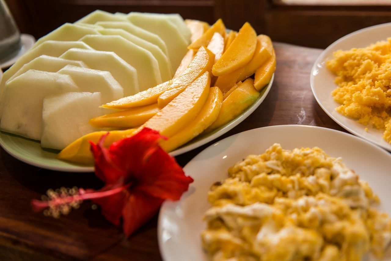 A plate of sliced mangoes and a plate of scrambled eggs.