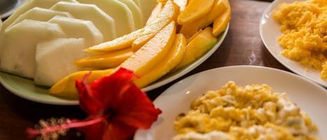 A plate of sliced mangoes and a plate of scrambled eggs.