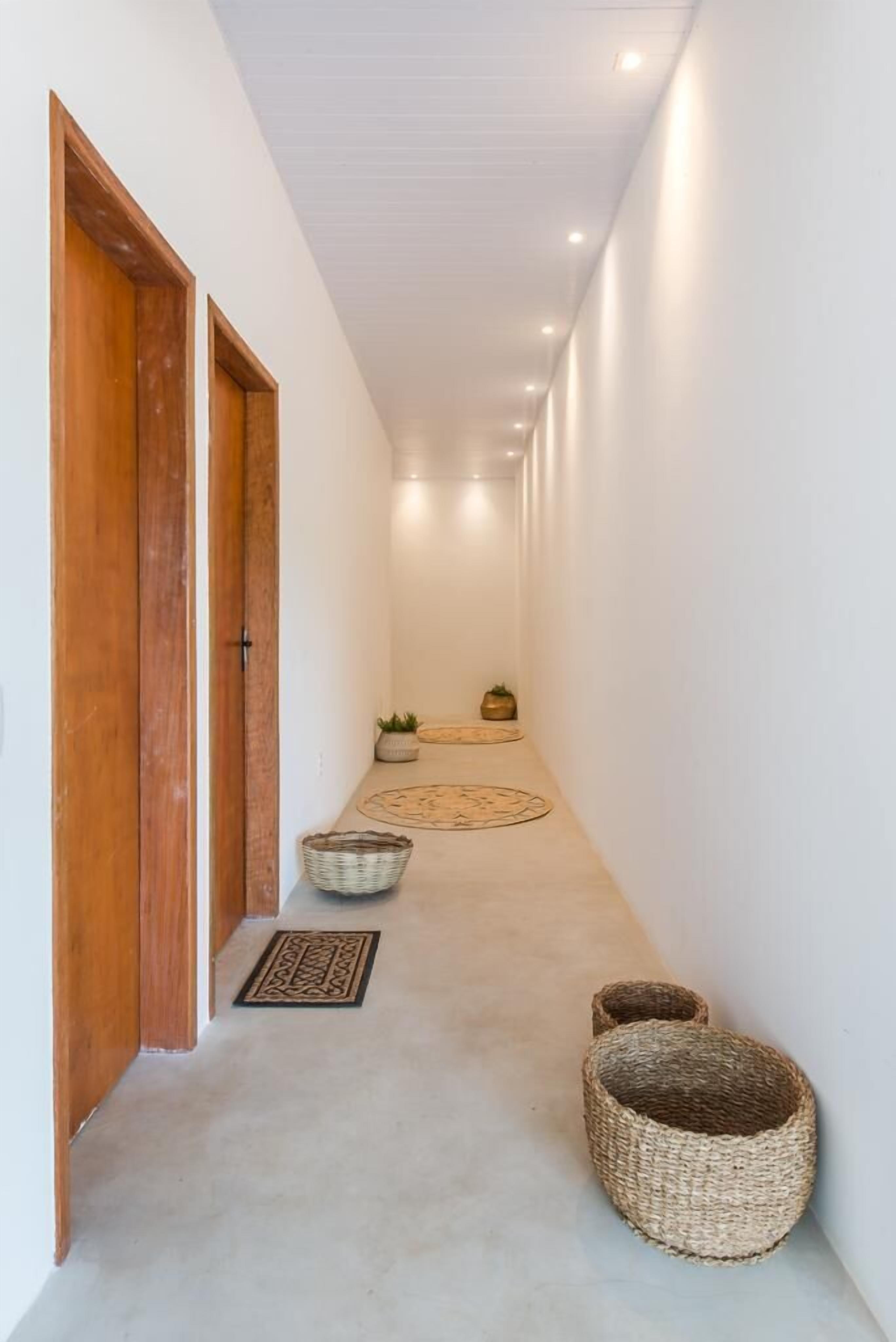 A corridor with wooden doors, a patterned rug, and woven baskets.