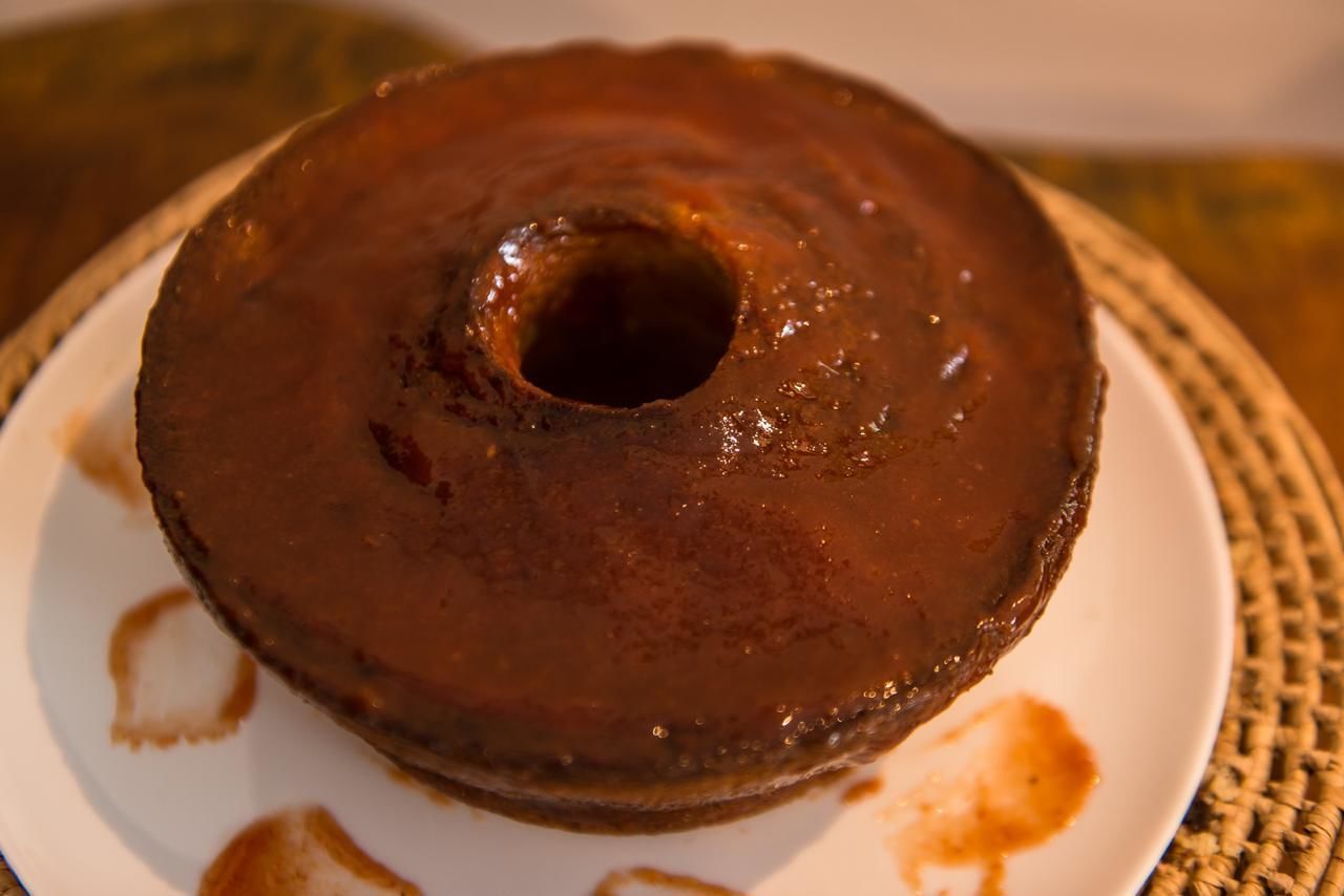 Un pastel bundt de chocolate sobre un plato blanco con un mantel estampado.