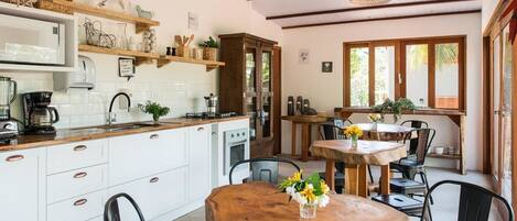 A kitchen with white cabinets, wooden countertops, and a dining area with a wooden table and chairs.