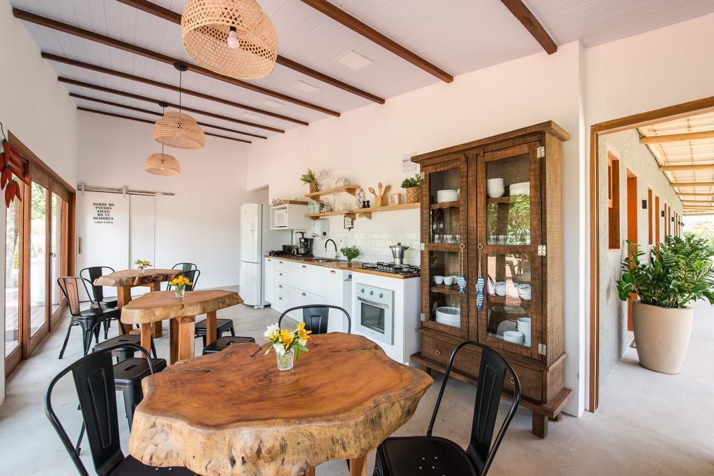 A modern kitchen with wooden cabinets, a dining area with a large wooden table, and hanging wicker lights.