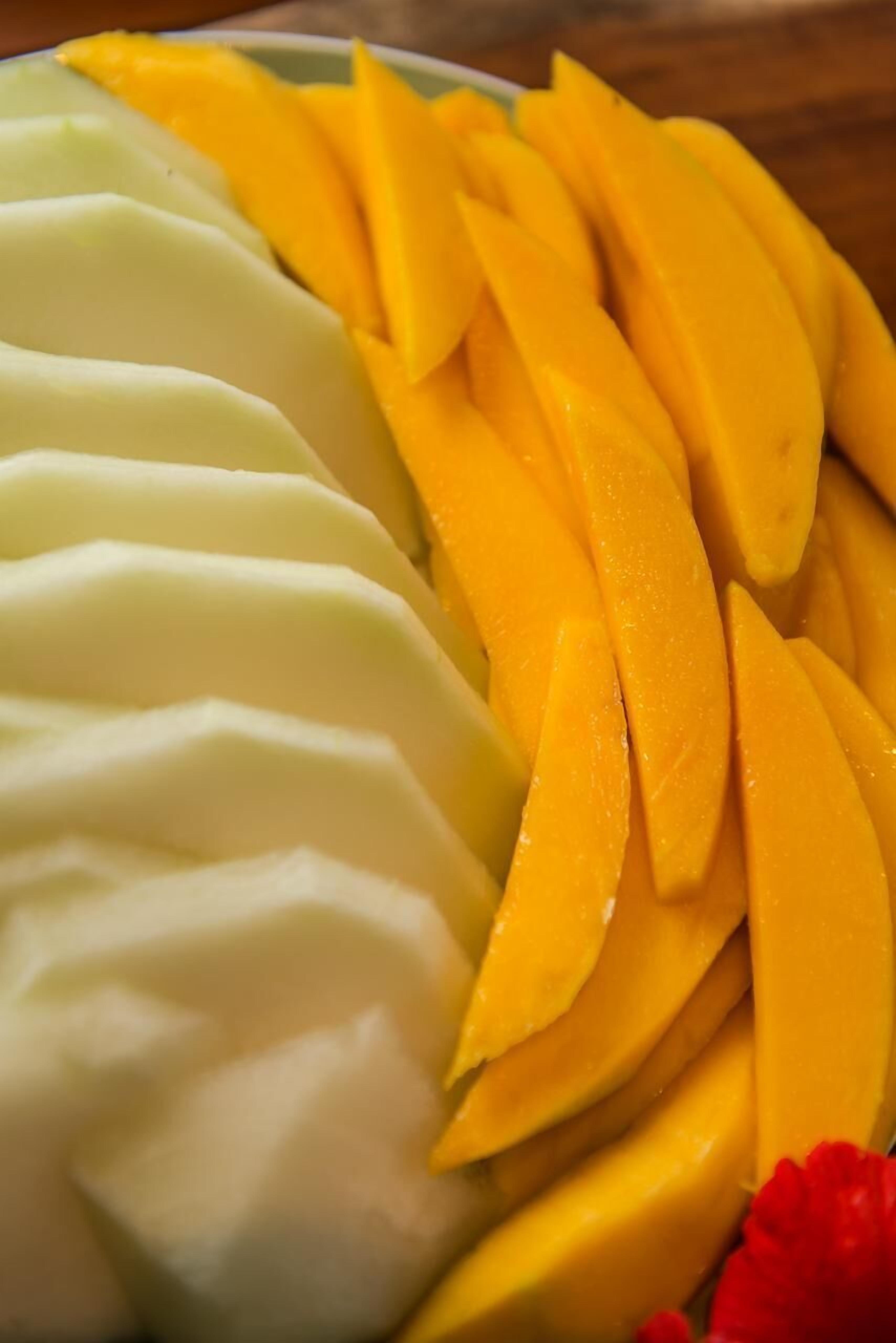 Une assiette contenant des tranches de mangue et une substance crémeuse, peut-être du yaourt ou une sorte de dessert.