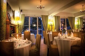 A dining area with round tables, chairs, and candlelit ambiance.