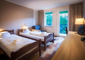 A hotel room with two wooden beds, a desk, and a chair.