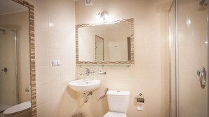 A bathroom with a toilet, sink, and shower.