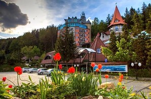 A hotel with a distinctive tower, a parking area, and a signboard.