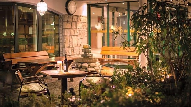 An outdoor seating area with tables and chairs, a stone wall, and a bench.