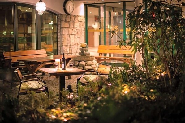 An outdoor seating area with tables and chairs, a stone wall, and a bench.