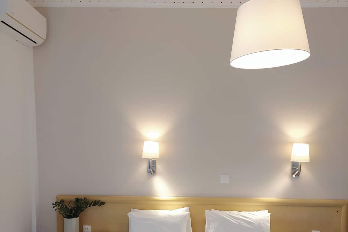 A hotel room with a large bed, two bedside tables, a wall-mounted lamp, and a ceiling light.