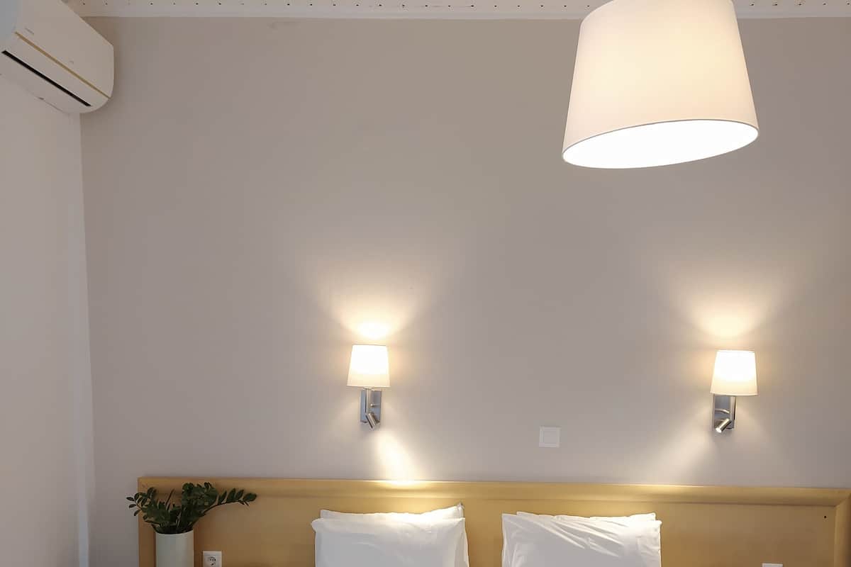 A hotel room with a large bed, two bedside tables, a wall-mounted lamp, and a ceiling light.