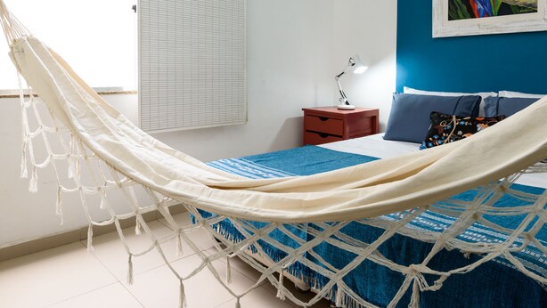 A hammock in a bedroom with a bed, a nightstand, a lamp, and a painting on the wall. - Omar do Rio - PM408 (Rio de Janeiro)