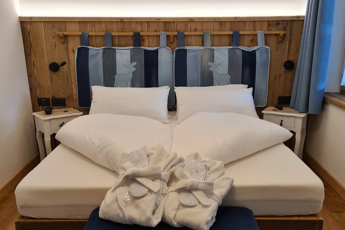 A bedroom with a wooden headboard, a bed with white bedding, and a bedside table with a lamp.