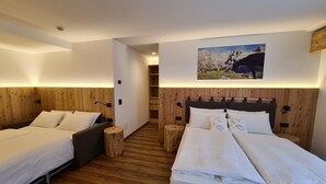 A hotel room with two beds, wooden paneling, a large mountain painting on the wall, and a small wooden stool. - Hotel Piedibosco (Moena)