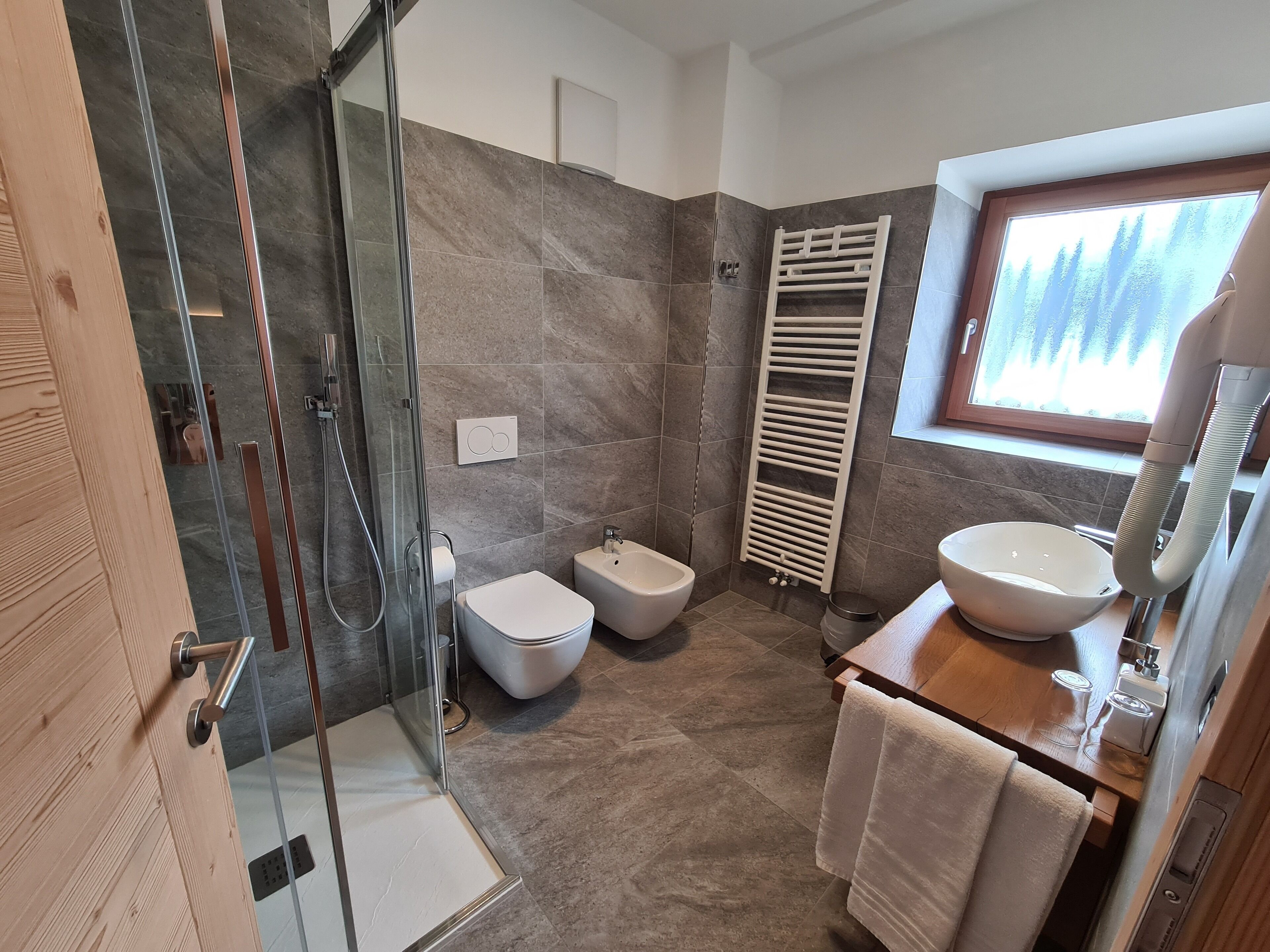 Une salle de bain moderne avec une douche à parois de verre, un bidet, des toilettes, un lavabo et un porte-serviettes.