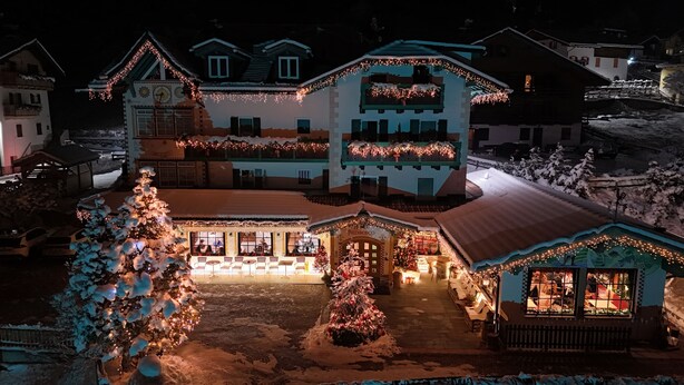A hotel with a traditional Alpine architectural style, featuring a central courtyard with a Christmas tree and a small outdoor seating area. - Hotel Piedibosco (Moena)