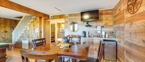 A wooden interior with a dining table, chairs, a kitchen area, and a staircase.
