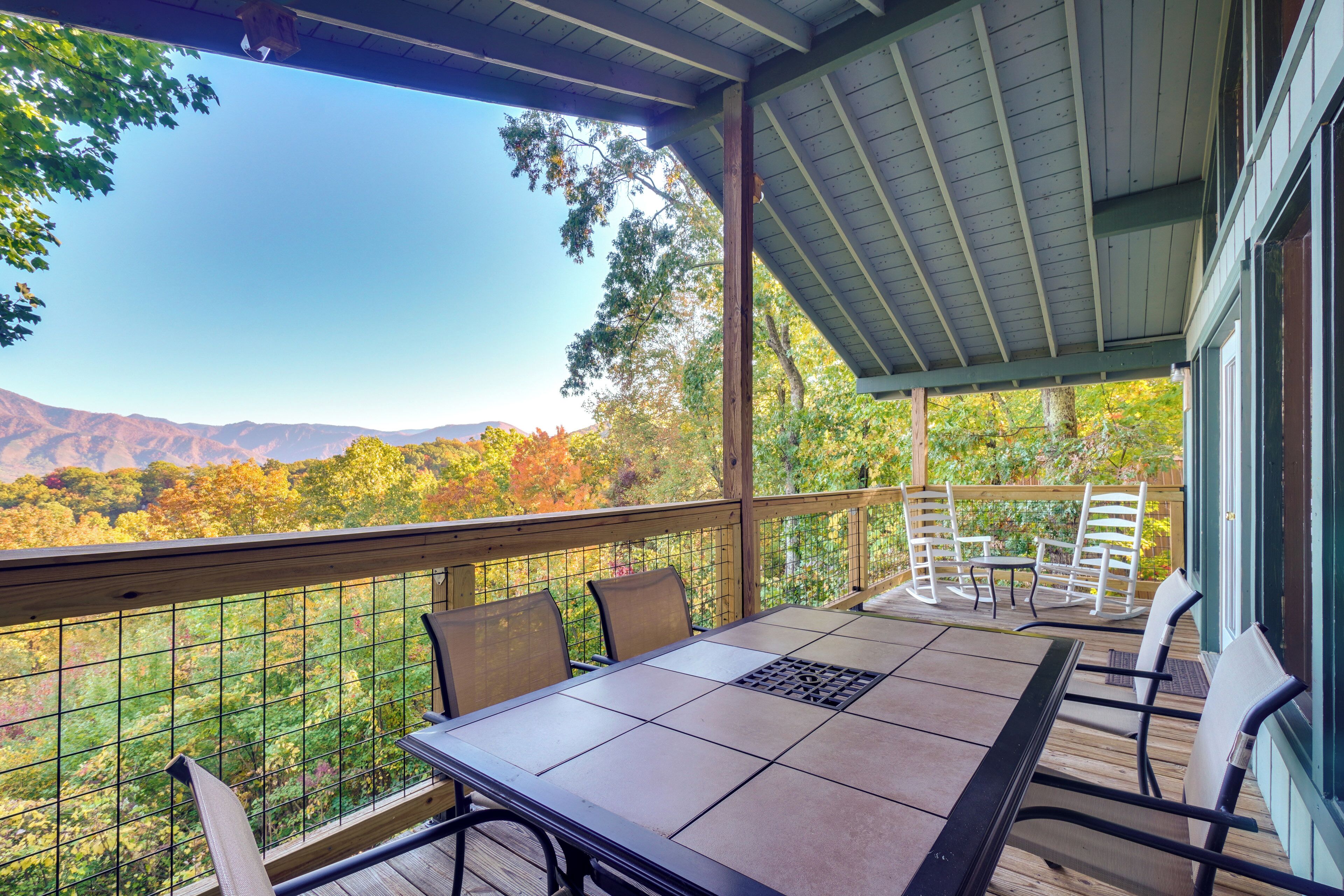 Une terrasse extérieure couverte, dotée d’une table et de chaises, qui offre une vue sur un paysage montagneux.