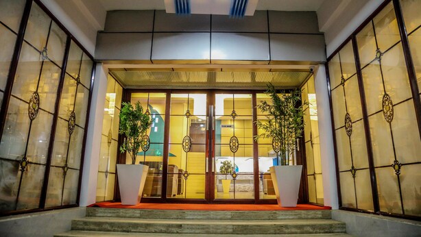 Una entrada tradicional al estilo japonés con puertas correderas, una alfombra roja y plantas en macetas.