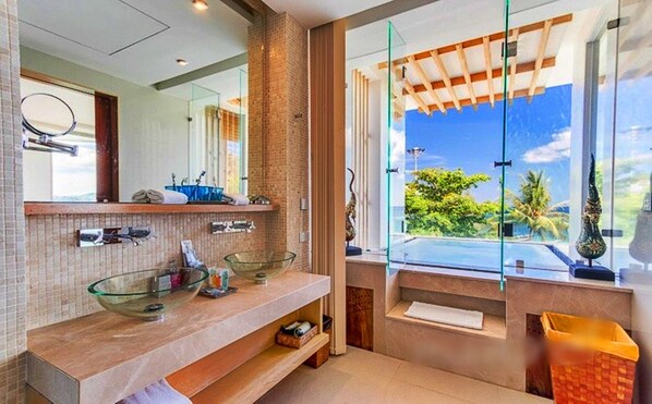 A modern bathroom with a glass bowl sink, a large mirror, and a view of the outdoors through a large window.