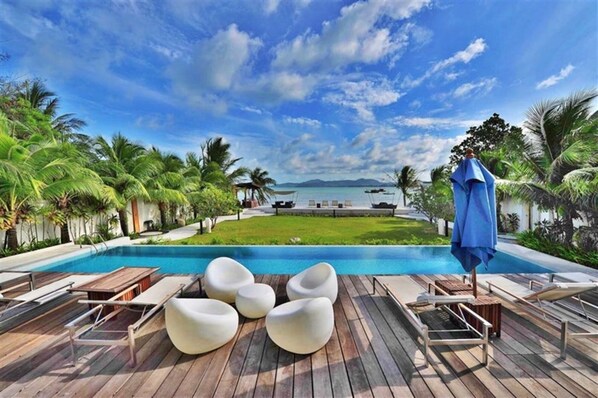 A poolside area with lounge chairs and a view of the ocean. - Luxurious Seafront  2 brm Penthouse with Spectacular views / unique design  (Thalang)