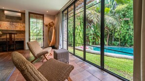 A spacious room with large windows overlooking a pool and lush greenery.