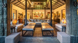 A spacious living area with a high ceiling, wicker furniture, and a large painting.