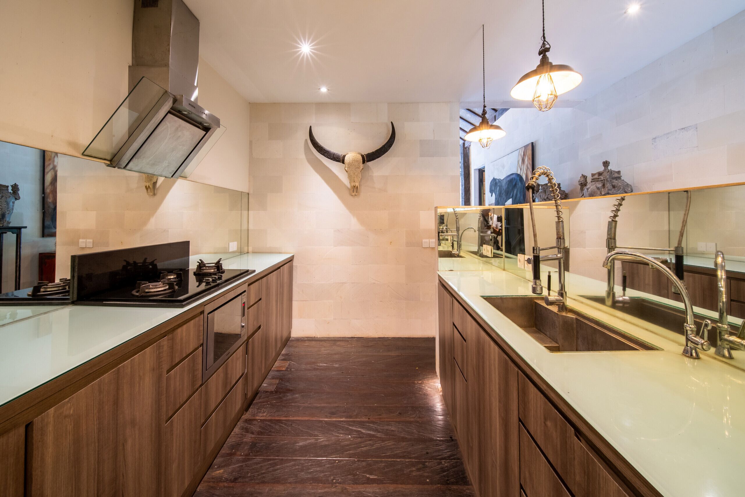A modern kitchen with wooden cabinets, a large island with a sink, and a bull skull decoration on the wall.