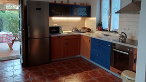 Une cuisine équipée d’un réfrigérateur, d’un four à micro-ondes et d’un four traditionnel, ainsi qu’un coin repas avec une table et des chaises.